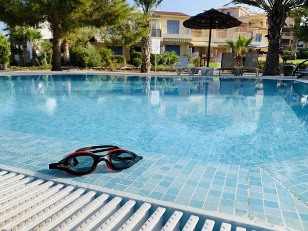 Lunettes de bain près de la piscine avec eau bleue — Photo