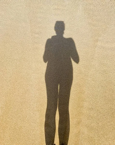 Woman shadow at sand. Walking on the beach. Self portrait. Abstract.