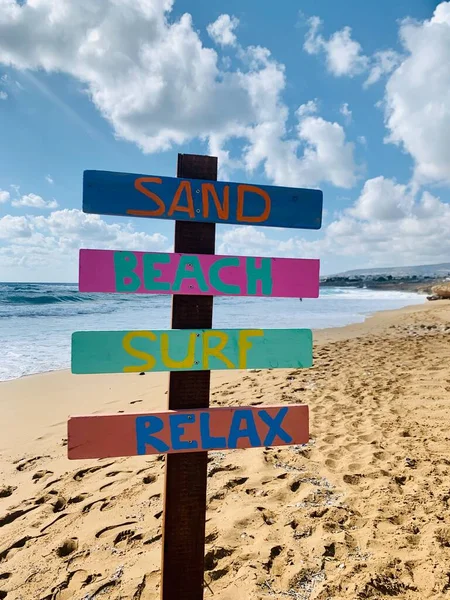 正午の光の日の青い海の上の砂浜でリラックスした名前の木製の看板 — ストック写真