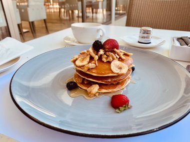 Beyaz tabak dolusu krep çilekli ahududu ve ballı kahvaltı.