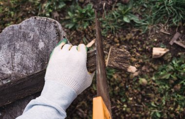 Tahta, tahta, tahta ve kirişler gördüm. Elindeki eldivenli el testeresi. İnşaat işi.
