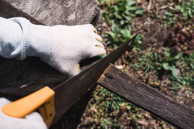 Tahta, tahta, tahta ve kirişler gördüm. Elindeki eldivenli el testeresi. İnşaat işi.