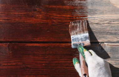 Yeni boyanmış ahşap arka plan, masa, çit. Boya fırçasıyla boya, eldiveni fırçayla tut..