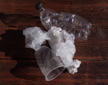 Plastik cam ve şişe. Koyu ahşap arka planda bir Celenfa paketi..