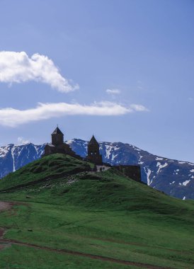 Gürcistan 'daki Gergeti Tapınağı' nın güzel manzarası. Vadideki Kazbek Dağı 'nın tepesindeki kilise açık mavi bir gökyüzüne karşı..