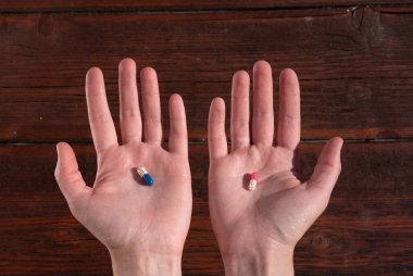 Bir insanın elinde iki tablet. Kırmızı ve mavi haplardan birini seç. İnsan sağlığı için vitaminler.