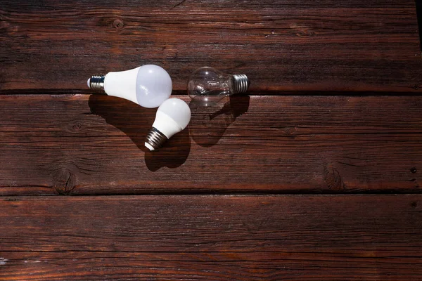 Three incandescent lamps on a wooden table. Old light bulbs, wooden background. Sorting of garbage.