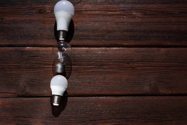 Three incandescent lamps on a wooden table. Old light bulbs, wooden background. Sorting of garbage.