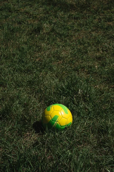 Soccer ball on the grass on the field. Football player, sports and recreation. Yellow and green leather ball.