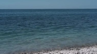 Küçük dalgalar kıyıya vuruyor. Pebble plajı, yaz tatili. Tatilde denizde temiz ve sessiz. Karadeniz kıyısı, Rusya.