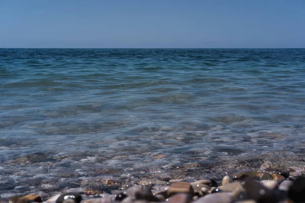 A wave rolls over the rocky shore. Black sea coast, pebble beach. Seashore.