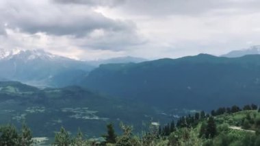 Kafkas dağlarının karlı tepelerinin panoramik manzarası. Bulutlu havada yeşil renkli bir vadi. Gürcistan Dağları, Svaneti.