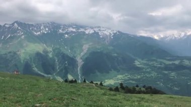 Bir Alman çoban köpeği karlı dağ zirvelerinin arka planında dinleniyor. Bir köpekle Kuzey Kafkasya 'nın Alp çayırlarına gezi..