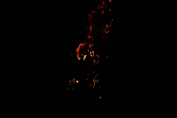 Bright firelight on a black background. The fire on a long exposure. Sparks and flames.