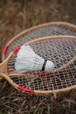 Tahta badminton raketleri ve beyaz tüylü bir top. Badminton oyunu. Hobiler ve açık hava eğlencesi.