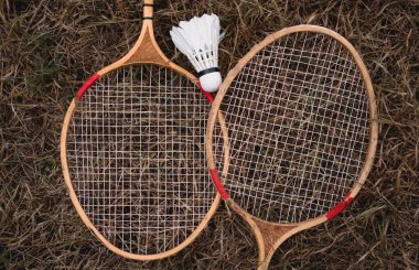 Tahta badminton raketleri ve beyaz tüylü bir top. Badminton oyunu. Hobiler ve açık hava eğlencesi.