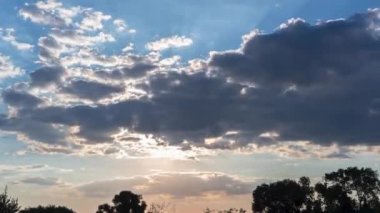 Gün batımının zamanı. Güneş ufuktan batar ve Cumulus bulutları gökyüzünde yüzer. Günün sonunda, yaz günbatımında. Köyde günbatımı gökyüzü. Hızlı atmosferik video.