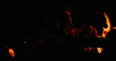 Ateşten kıvılcımlar ve siyah arka planda kızgın kömürler. Kamp ateşi, grafik yerleştirme için ateş. Küller ve kömürler, ateşten çıkan duman.