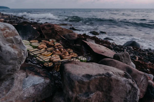 A variety of vegetables and mushrooms grilled over a fire on a grill. Vegetarian barbecue on the fire on the beach. Delicious and healthy food without meat.