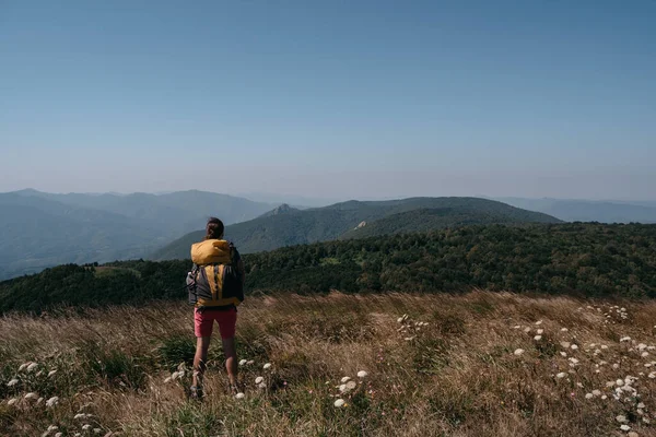 Μια Γυναίκα Ταξιδιώτης Στέκεται Στα Βουνά Ένα Μεγάλο Κίτρινο Σακίδιο — Φωτογραφία Αρχείου