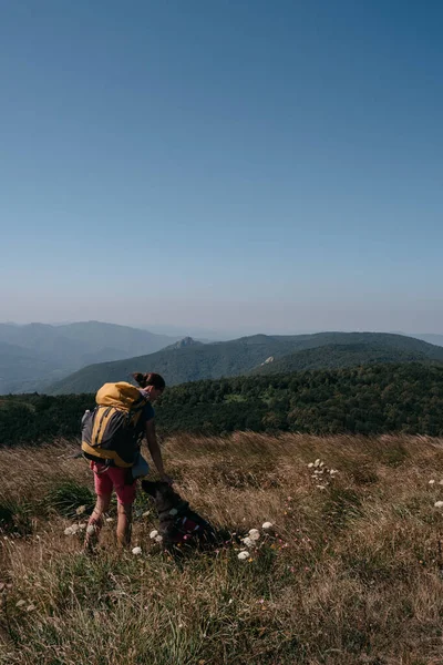 Bir kız gezgin ve Alman çoban köpeği bir tepede durup etraftaki dağlara bakıyorlar. Bir köpek gezgini ve sırt çantalı insan sahibi ulusal parkta yürüyor ve doğanın tadını çıkarıyorlar..