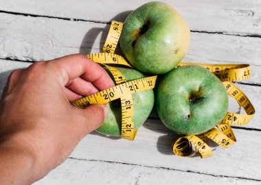 Bir insan yeşil taze elmalara ve üzerinde 2021 rakamları olan sarı bir kurdeleye dokunur. Sağlıklı ve zindelik için vitaminli lezzetli ve sağlıklı yiyecekler..