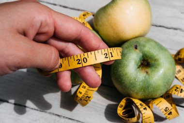 Bir insan yeşil taze elmalara ve üzerinde 2021 rakamları olan sarı bir kurdeleye dokunur. Sağlıklı ve zindelik için vitaminli lezzetli ve sağlıklı yiyecekler..