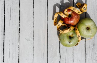 Beyaz ahşap arka planda üç elma sarısı, yeşil ve kırmızı ve sarı esnek kurdele. Lezzetli ve sağlıklı yiyecekler mutfak masasında..