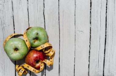 Beyaz ahşap arka planda üç elma sarısı, yeşil ve kırmızı ve sarı esnek kurdele. Lezzetli ve sağlıklı yiyecekler mutfak masasında..