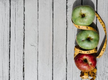 Beyaz ahşap arka planda üç elma sarısı, yeşil ve kırmızı ve sarı esnek kurdele. Lezzetli ve sağlıklı yiyecekler mutfak masasında..