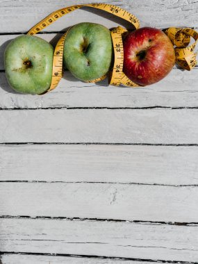 Beyaz ahşap arka planda üç elma sarısı, yeşil ve kırmızı ve sarı esnek kurdele. Lezzetli ve sağlıklı yiyecekler mutfak masasında..