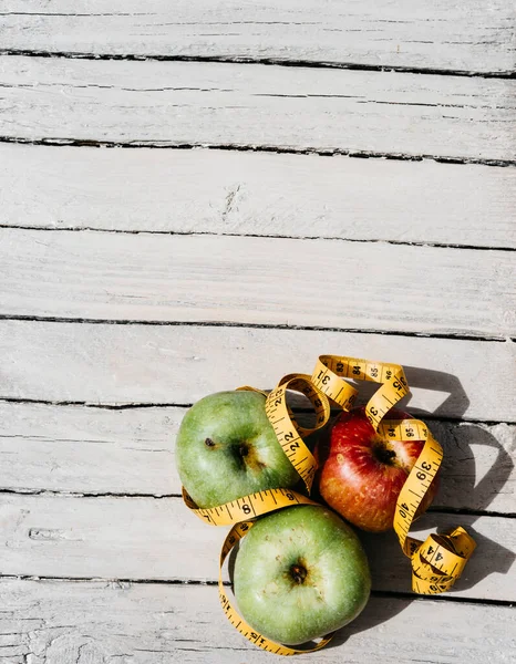 Beyaz ahşap arka planda üç elma sarısı, yeşil ve kırmızı ve sarı esnek kurdele. Lezzetli ve sağlıklı yiyecekler mutfak masasında..