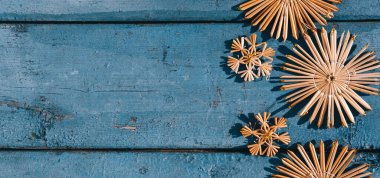 Güzel mavi Noel afişi, el yapımı saman ağacı oyuncakları kar taneleri. Ahşap Noel arka planı, üst manzara. Yeni yılın arka planında metin için yer.