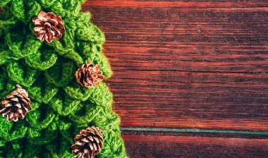 Kahverengi ahşap arka planda çam kozalakları olan el yapımı yeşil Noel ağacı. Güzel yeni yıl afişi. Mutlu yıllar ve mutlu Noeller..