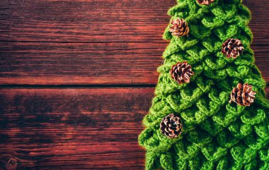 Kahverengi ahşap arka planda çam kozalakları olan el yapımı yeşil Noel ağacı. Güzel yeni yıl afişi. Mutlu yıllar ve mutlu Noeller..