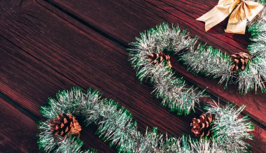 Noel ağacı şeklinde parlak yeşil bir süs koni ve ahşap bir arka planda altın bir fiyonk. Güzel bir Noel geçmişi. Mutlu yıllar ve mutlu Noeller..