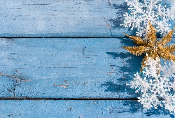 Beyaz kar taneleri ve parlak yıldızlı güzel mavi Noel arka planı. Ahşap Noel arka planı, üst manzara. Yeni yılın arka planında metin için yer.