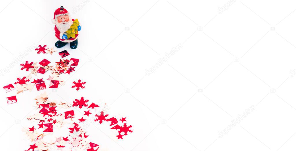 Small Santa figure and sequins on a white background. Happy new year and merry Christmas. Red and orange shiny confetti, Christmas background.