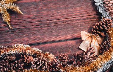 Güzel yatay Noel arkaplanı. Tahta arka planda sarı, turuncu, altın ve gümüş renkli parlak süsler. Harfler ve tasarım için bir sürü boş alan, çam kozalaklı Noel kartı..