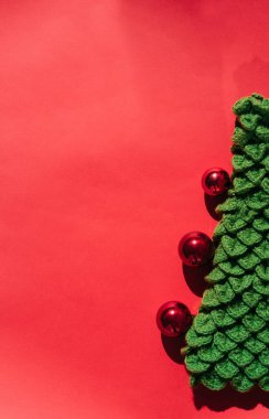 Güzel kırmızı gradyan Noel arkaplanı ve mesaj için bir sürü boş alan. Küçük parlak kırmızı topları olan yeşil el yapımı Noel ağacı. Noel oyuncağı.