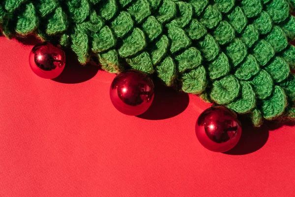 Beautiful red gradient Christmas background and lots of empty space for text. Green handmade knitted Christmas tree with small shiny red balls. Christmas toy.