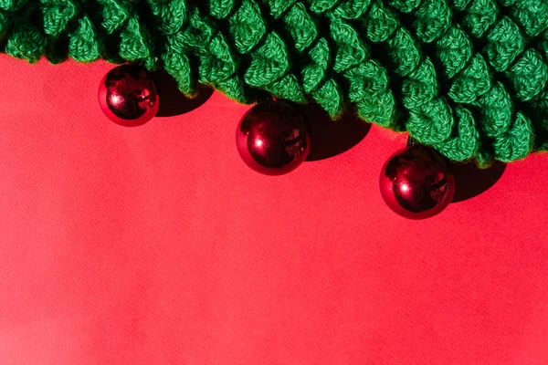 Beautiful red gradient Christmas background and lots of empty space for text. Green handmade knitted Christmas tree with small shiny red balls. Christmas toy.