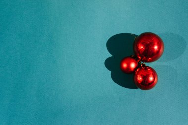 Açık mavi arka planda üç kırmızı parlak toplar. Güzel minimalist Noel arkaplanı ve harfler için bir sürü boş alan. Noel ağacı için Noel oyuncakları ve süslemeleri.