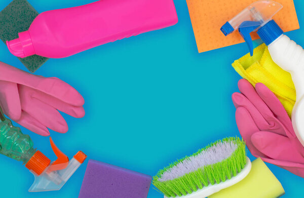 Colorful cleaning set for different surfaces in kitchen, bathroom and other rooms. Empty place for text or logo on blue background. Cleaning service concept. Early spring regular clean up. Top view.