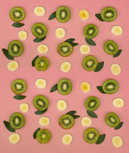 Kolorowy wzór owoców świeżych kiwi i plasterki bananów na różowym tle. Z widoku z góry — Zdjęcie stockowe