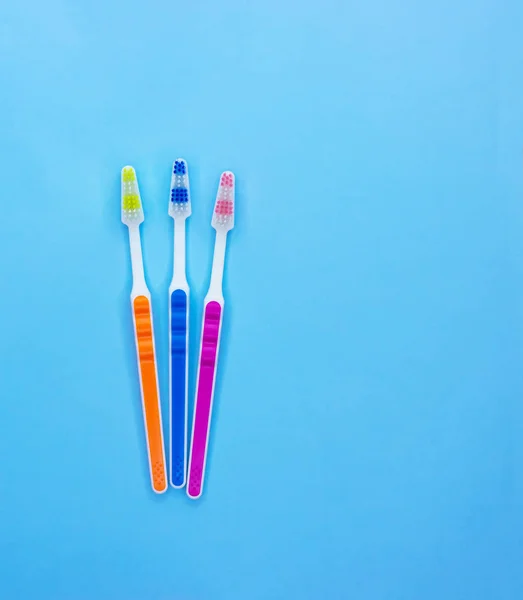 Cepillos de dientes multicolores sobre un fondo azul con espacio para copiar. Acostado. Vista superior . — Foto de Stock