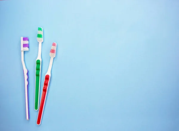 Cepillos de dientes multicolores sobre un fondo azul con espacio para copiar. Acostado. Vista superior . — Foto de Stock