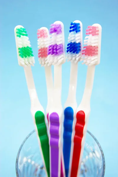 Cepillos de dientes en un vaso, fondo azul — Foto de Stock