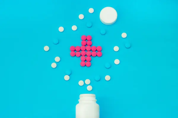 Різнокольорові таблетки з білих банок на синьому фоні — стокове фото