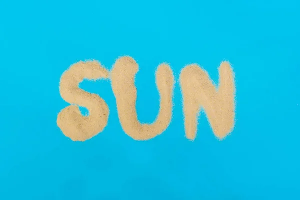 Nápis slunce vyrobený z písku na modrém pozadí — Stock fotografie
